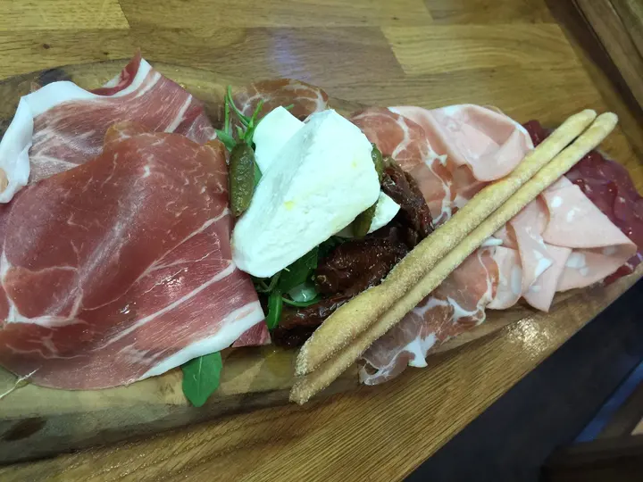 Antipasto misto with Parma ham, bresaola, mozzarella and grissini on a board