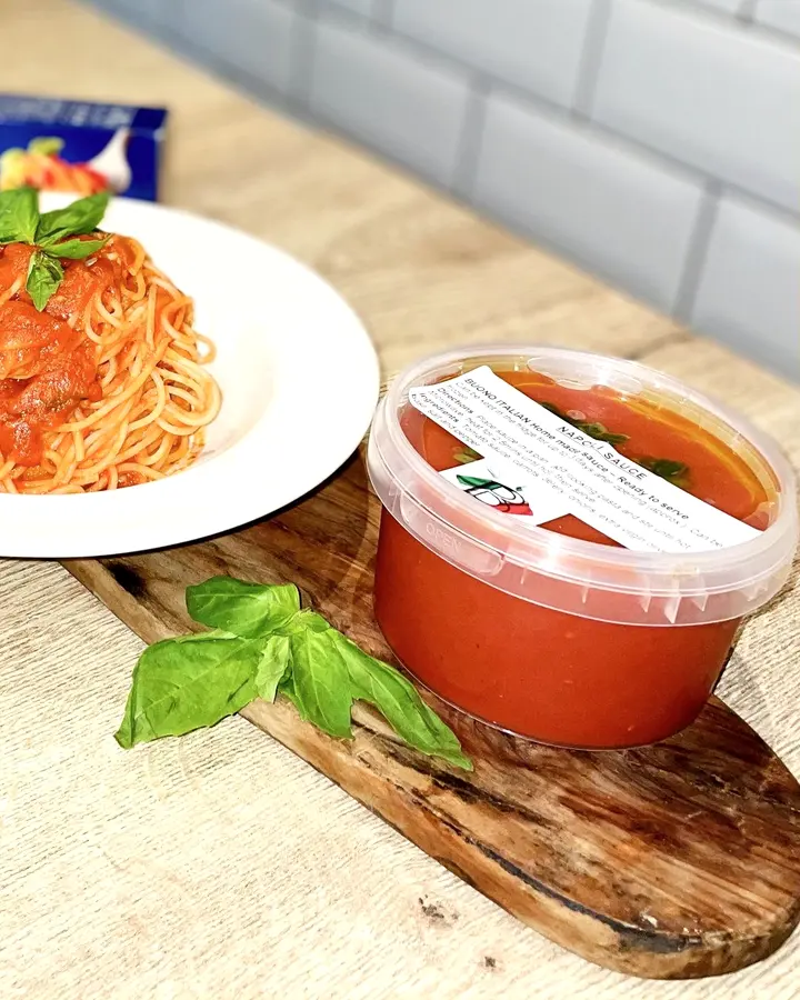 A tub of Buono homemade Napoli sauce with a plate of spaghetti